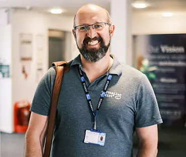 Mature male student smiling in corridor of college