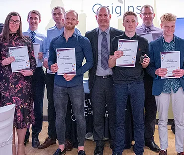 Large group of apprentices holding certificates either side of the College's Head of Apprenticeships