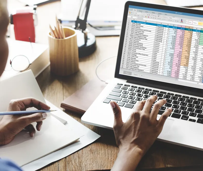 Close up of a person on a laptop working on a spreadsheet.