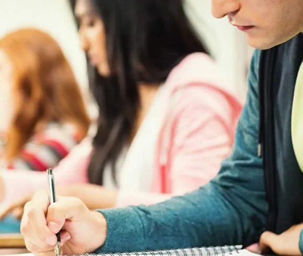 Close up of students in classroom writing notes