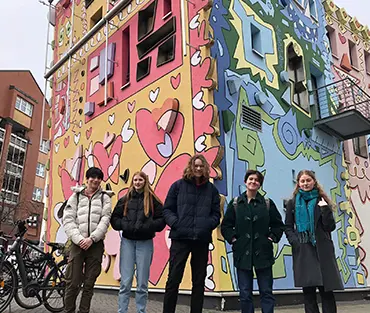 Students standing in front of graffitied building