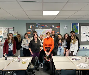 Group of students, staff and employers standing together smiling in classroom